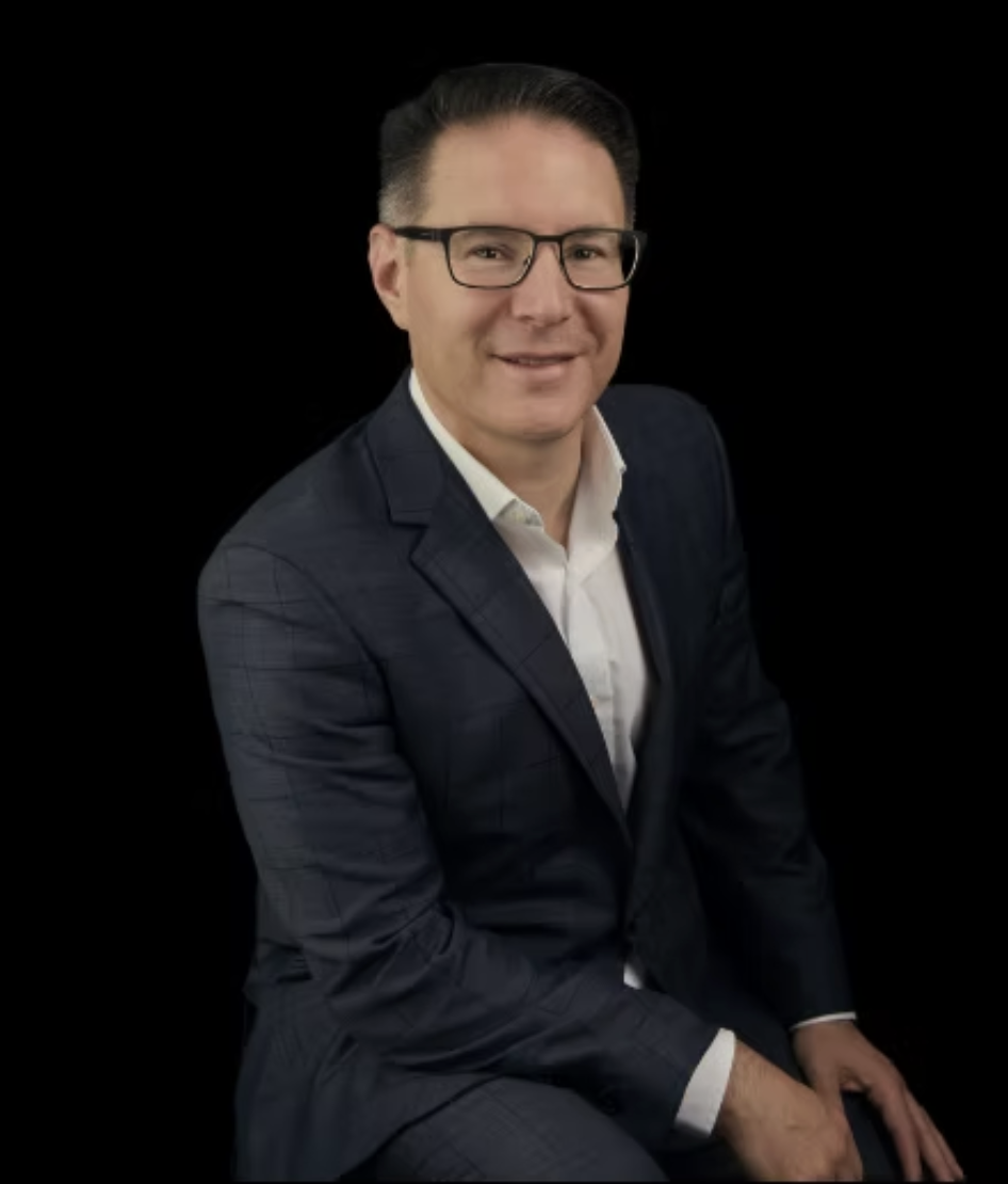 Michael Moreno, seated in a navy blazer and white shirt, smiling